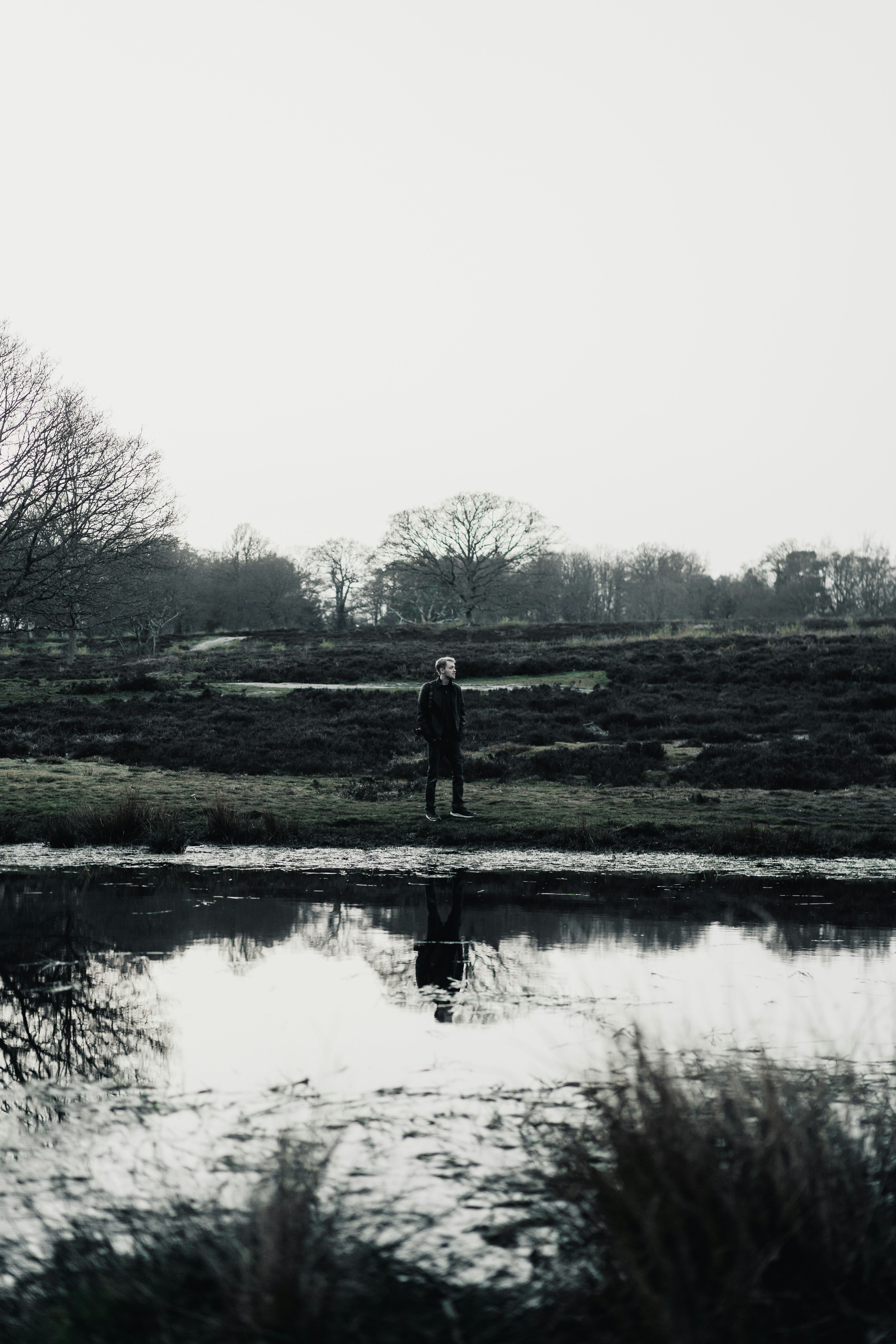 man standing on green grass field near lake during daytime